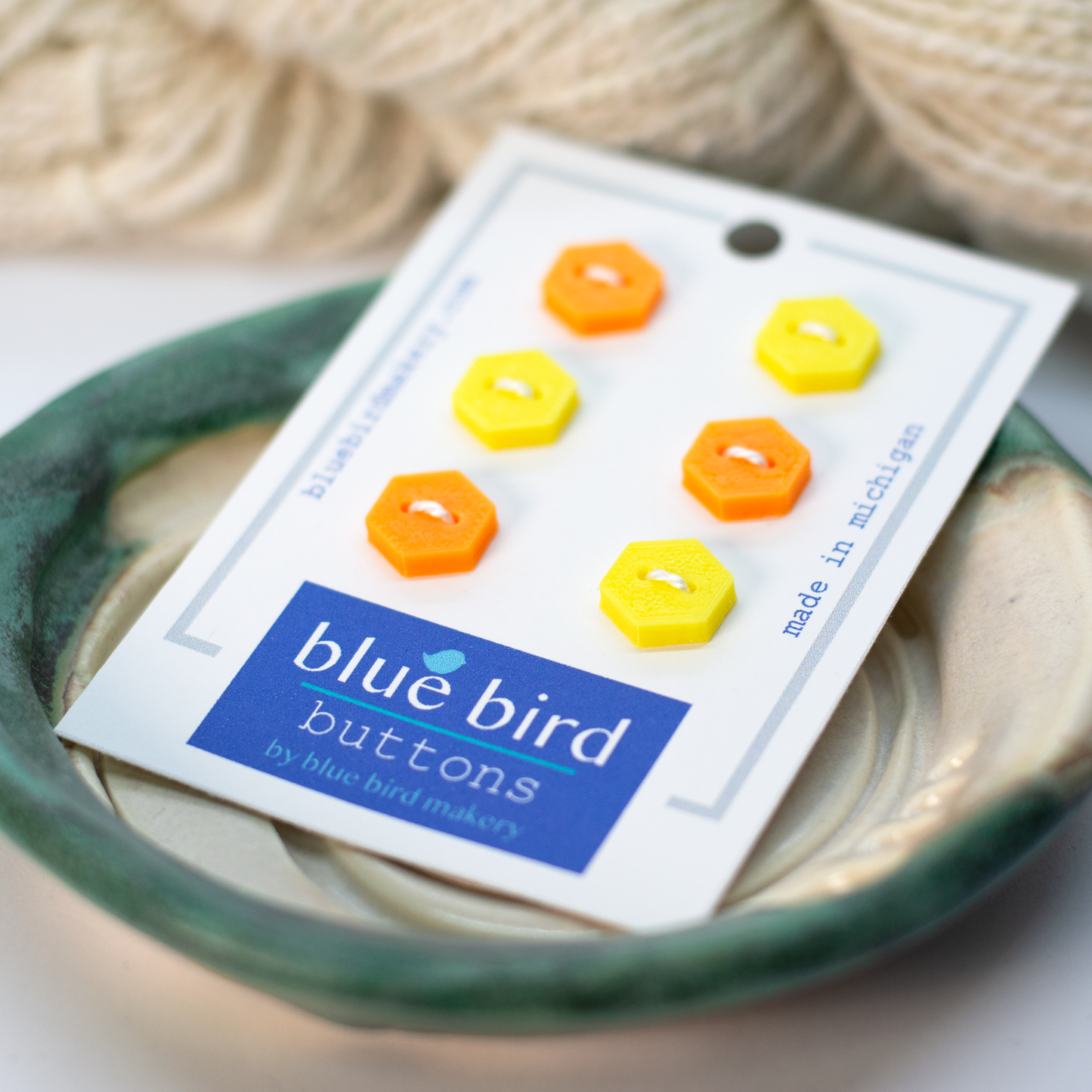 Blue Bird Makery button set featuring six vibrant hexagonal buttons in orange and yellow on a card