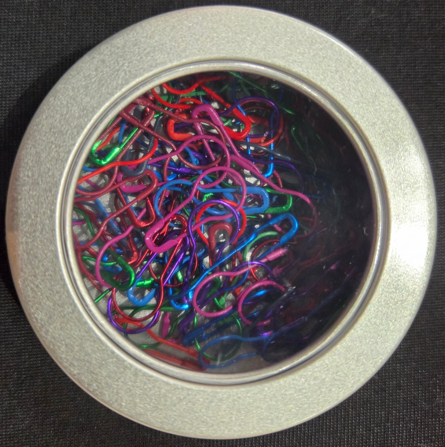 AriYARN stitch marker set in round silver tin with clear lid showing colorful loop stitch markers for knitting