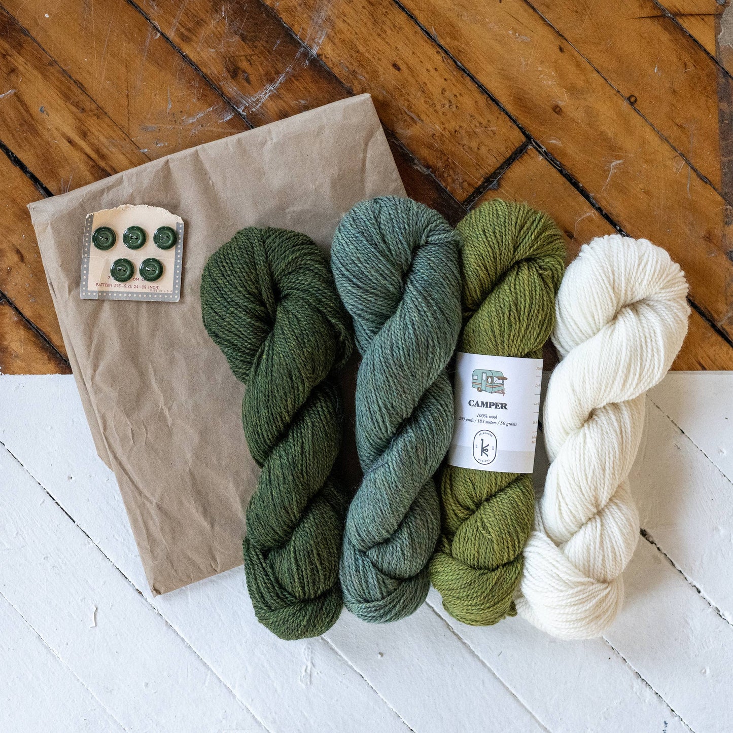 Kelbourne Woolens fingering weight 100% wool yarn skeins in green and cream with green buttons and kraft paper