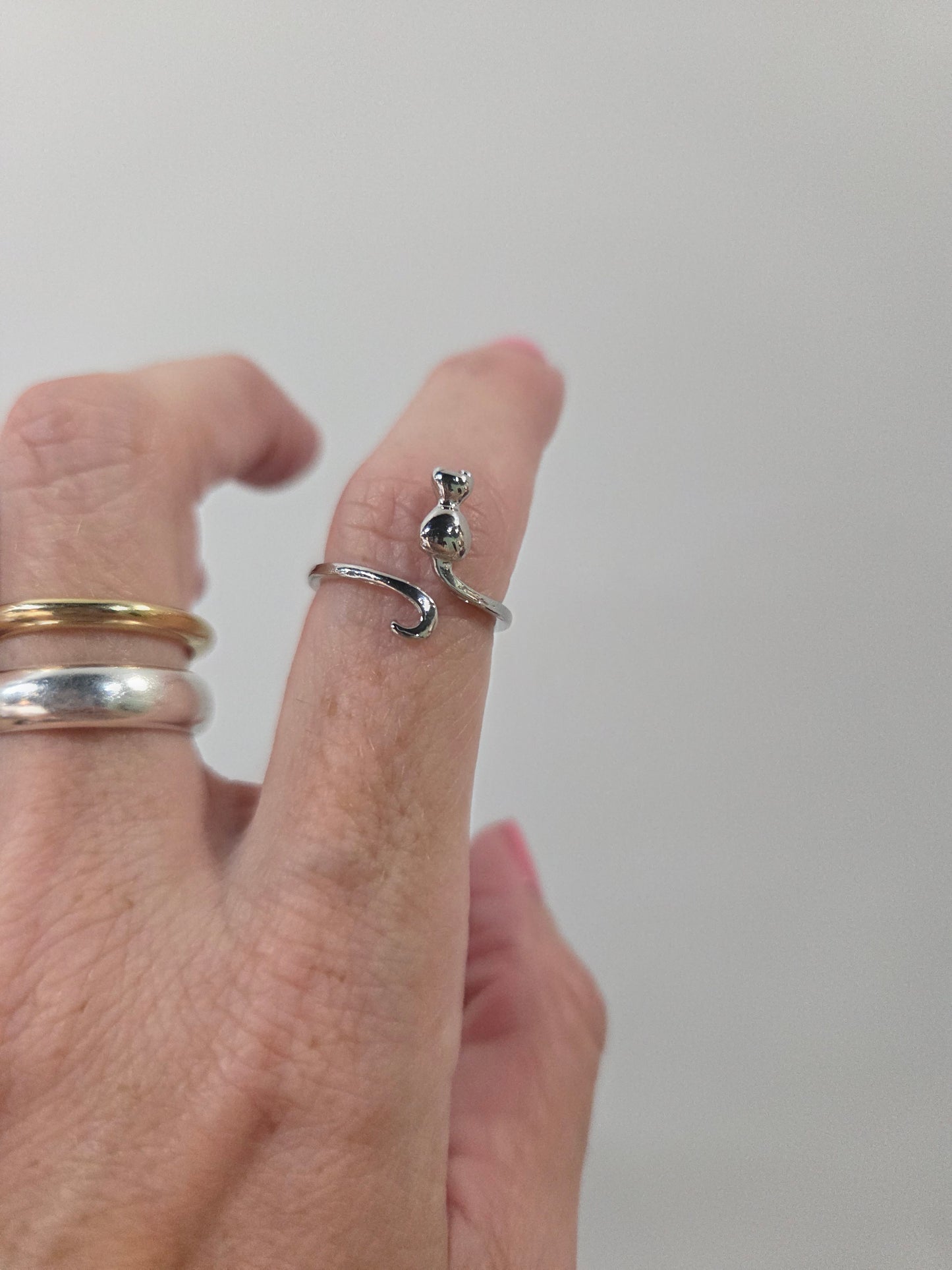 Silver cat shaped adjustable ring on index finger used as crochet accessories for tension control