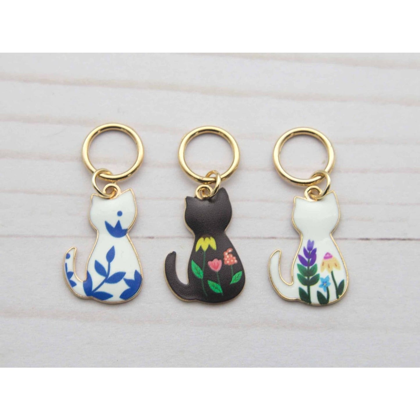 Set of three cute cat stitch markers for crocheting with floral designs and gold rings