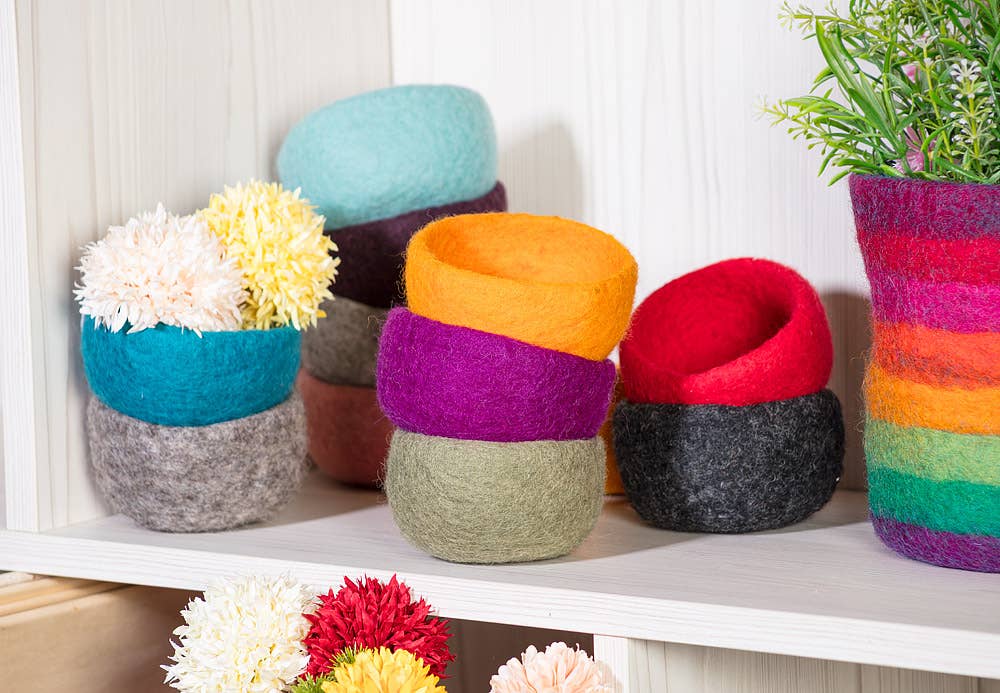 Colorful handmade yarn storage bowls in various sizes and patterns for organizing craft supplies