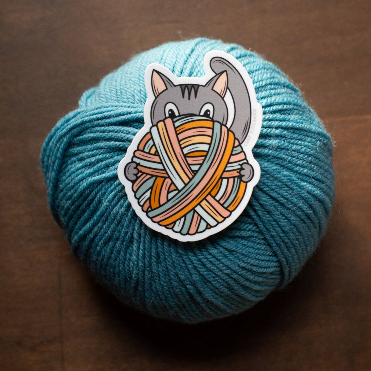Happy cat sticker on teal yarn ball for crafting enthusiasts and cat lovers