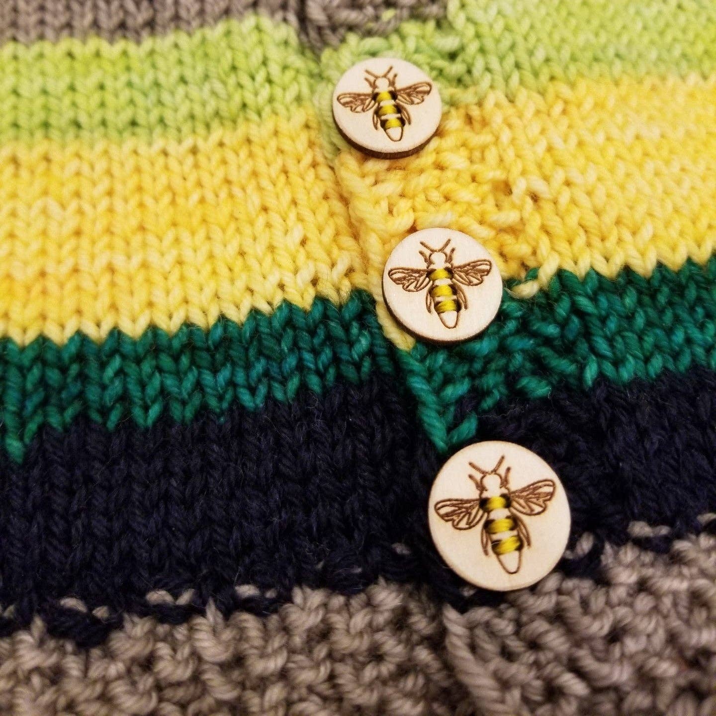 Wooden buttons featuring honey bee design on a colorful knitted garment