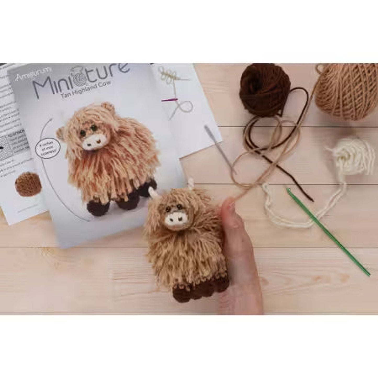 Leisure Arts miniature crochet cow kit with tan yarn, pattern guide, and crochet supplies