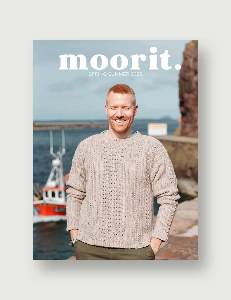 Moorit Magazine crochet patterns cover showing smiling man wearing textured hand crochet sweater by a harbor