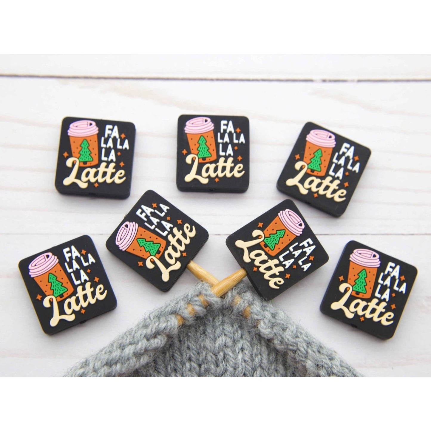 Fa La La La Latte stitch stopper set of seven black rectangular knitting stoppers with holiday latte design on gray project