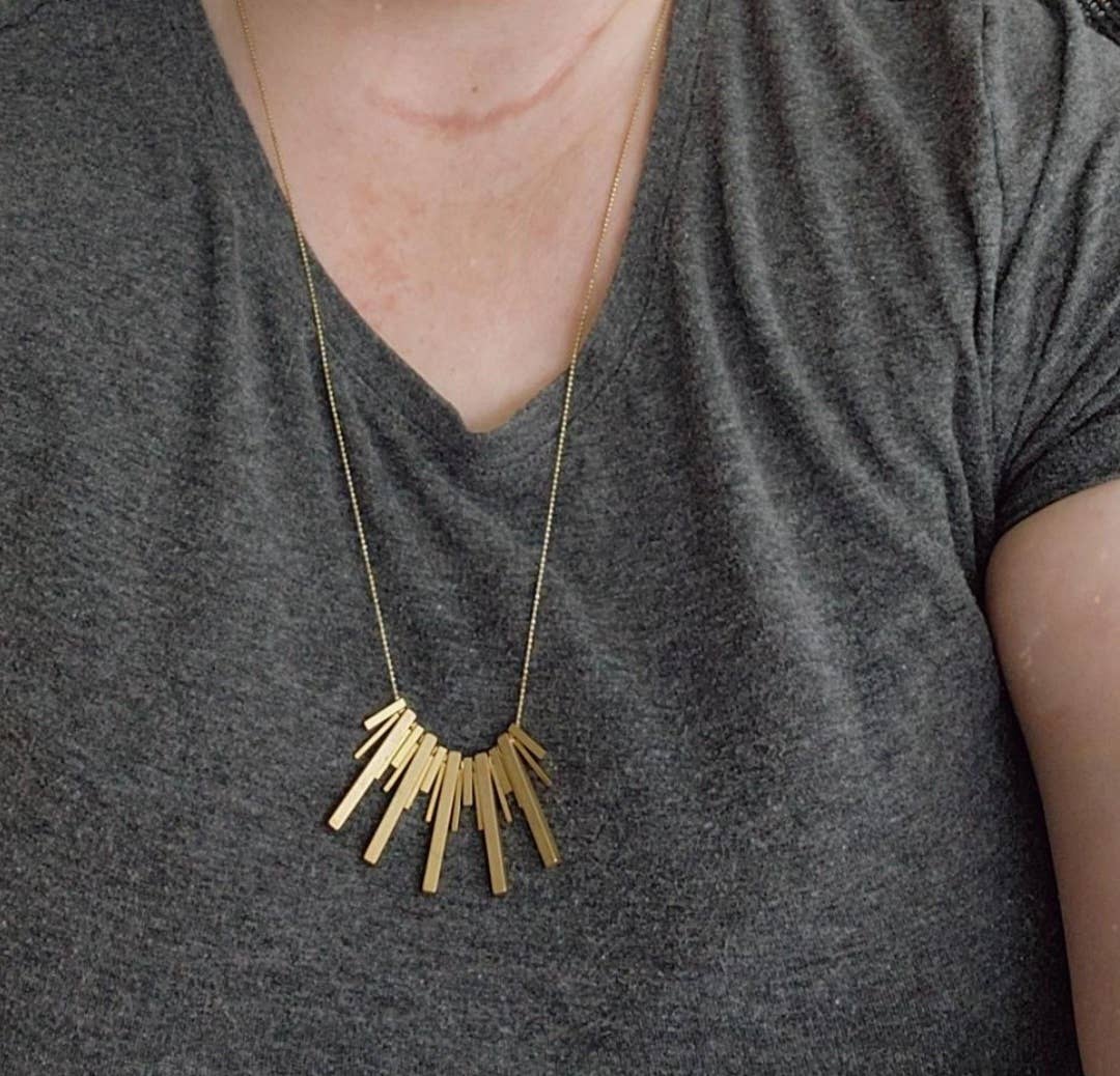 Sara Sela Jewelry beaded edgy fashion necklace gold bar pendant on fine chain worn with gray t shirt