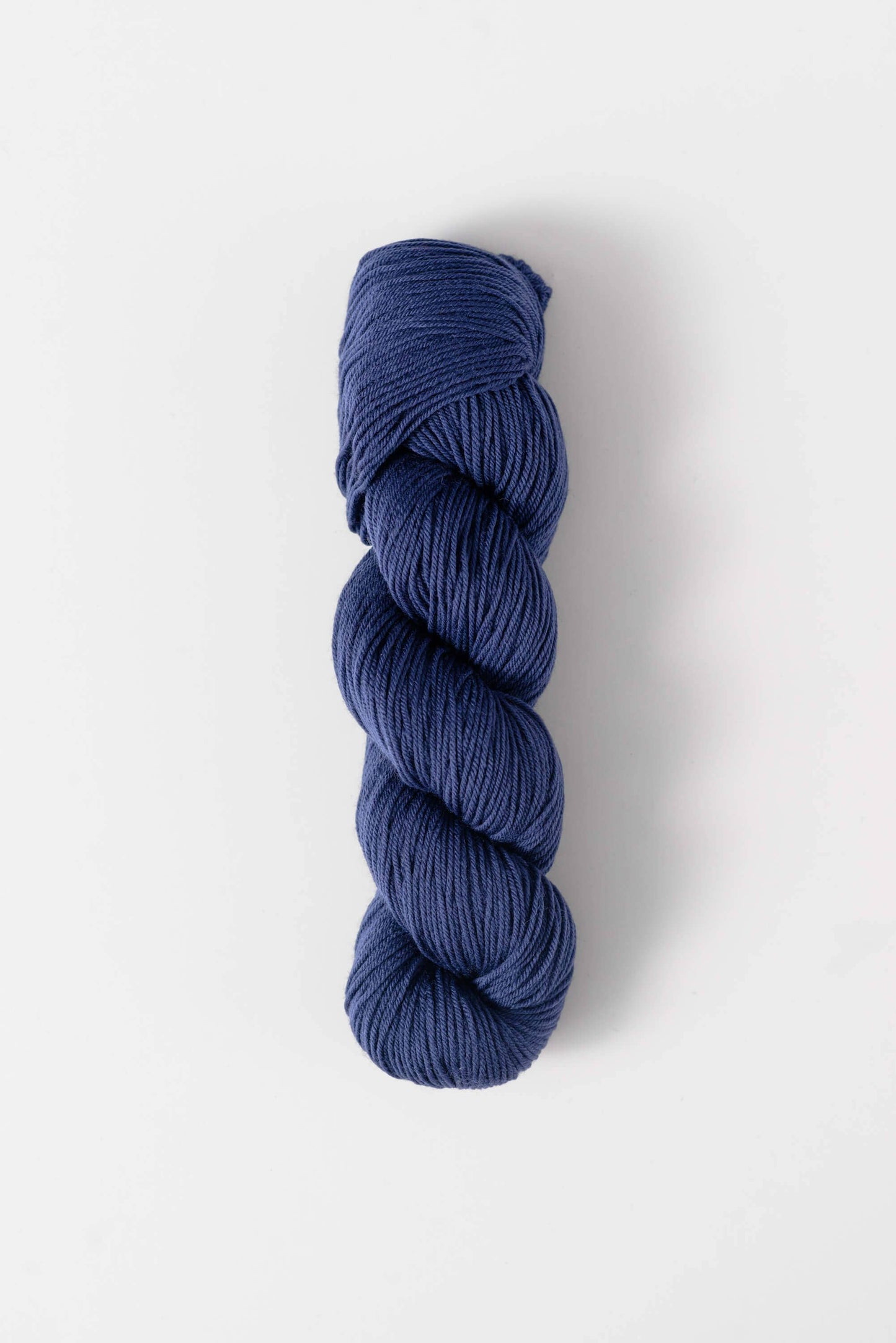 Quince and Co superwash merino fingering yarn in rich navy blue twisted skein