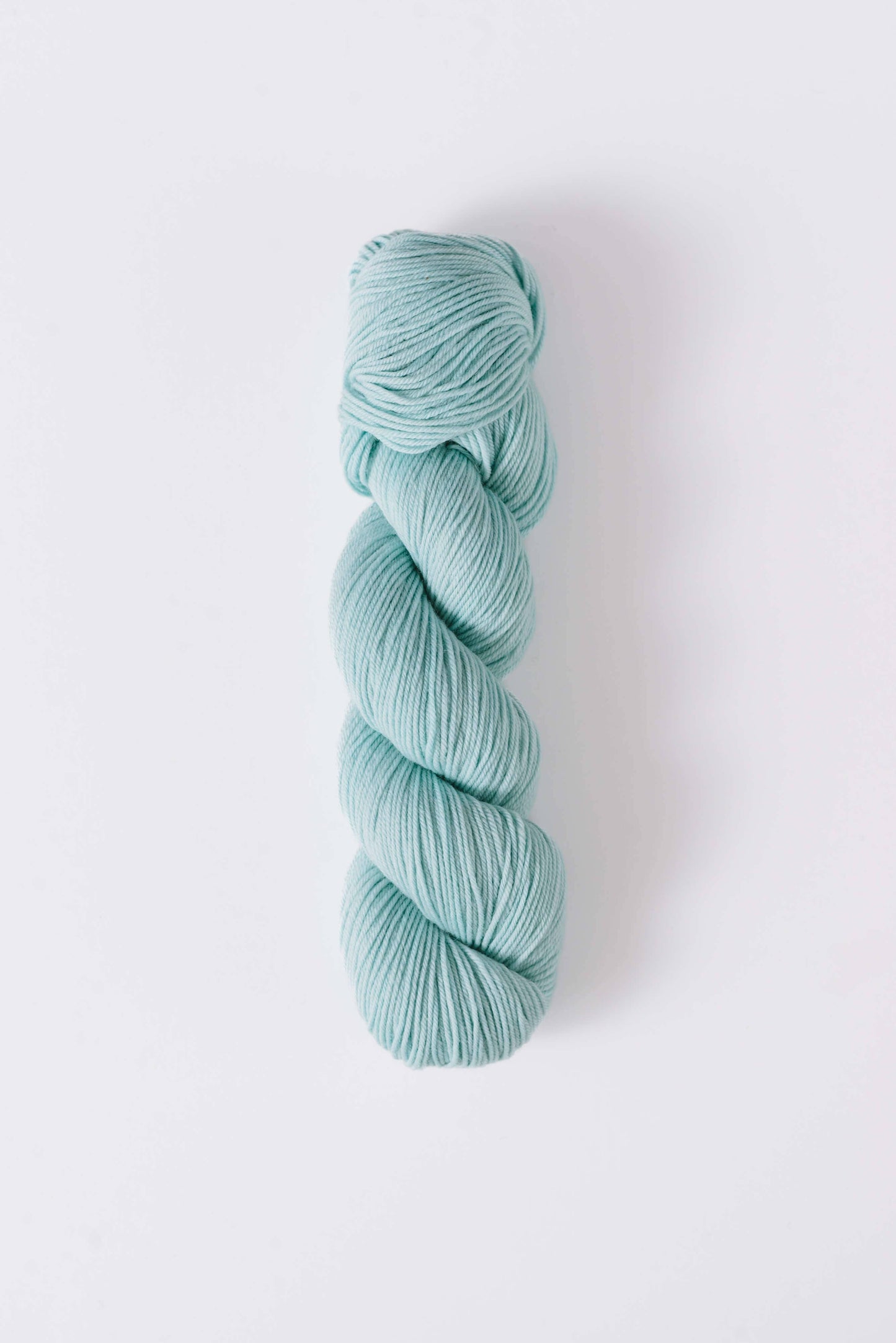 Quince & Co. light blue superwash merino fingering yarn skein on white background