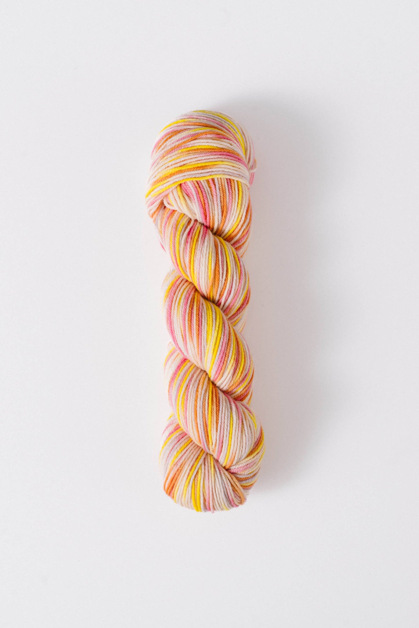 Quince & Co superwash merino fingering yarn in variegated pink yellow and orange colors