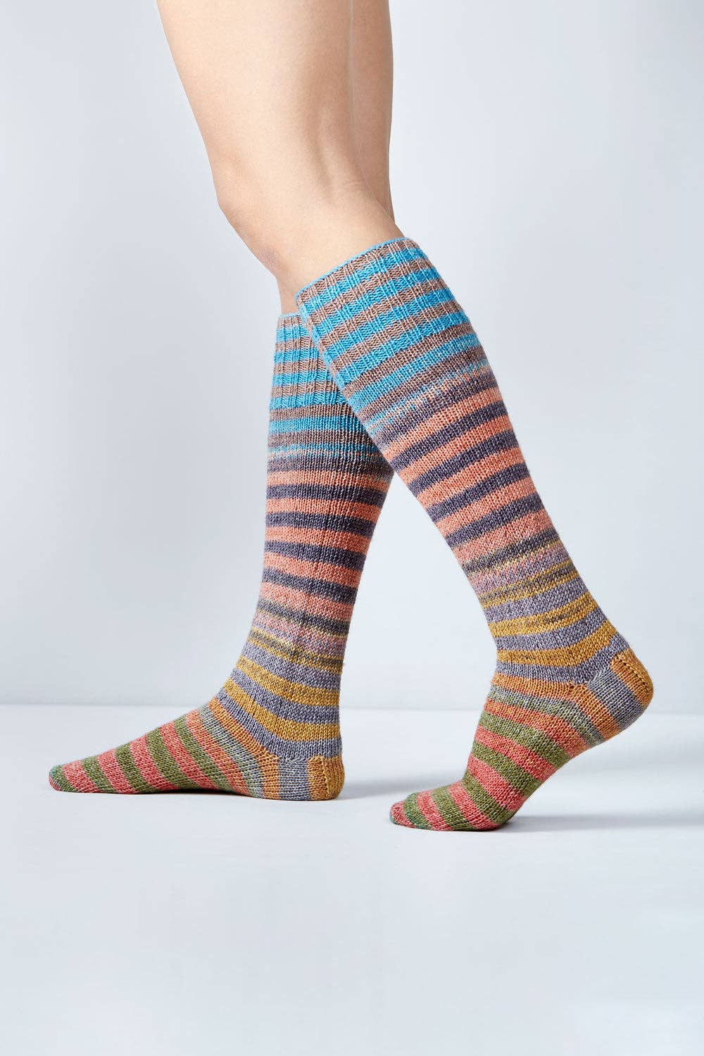 Colorful knitted socks made with Urth Yarns Uneek Sock Kit for Knitting, showcasing vibrant stripes