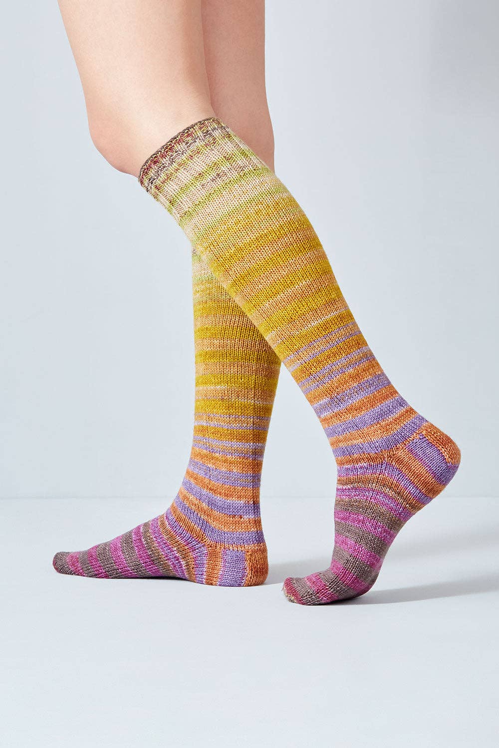 Knee-high socks made with Uneek Sock Kit by Urth Yarns in vibrant multicolored stripes