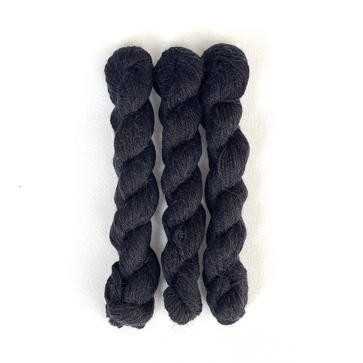 Three skeins of Kelbourne Woolens Perennial Minis yarn in deep black color for knitting and crochet projects