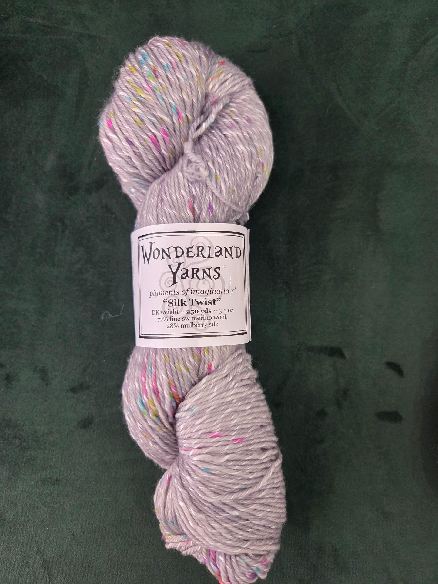 Frabjous Fibers light lavender tweed yarn skein with multicolored speckles on dark green backdrop Wonderland Yarns Silk Twist
