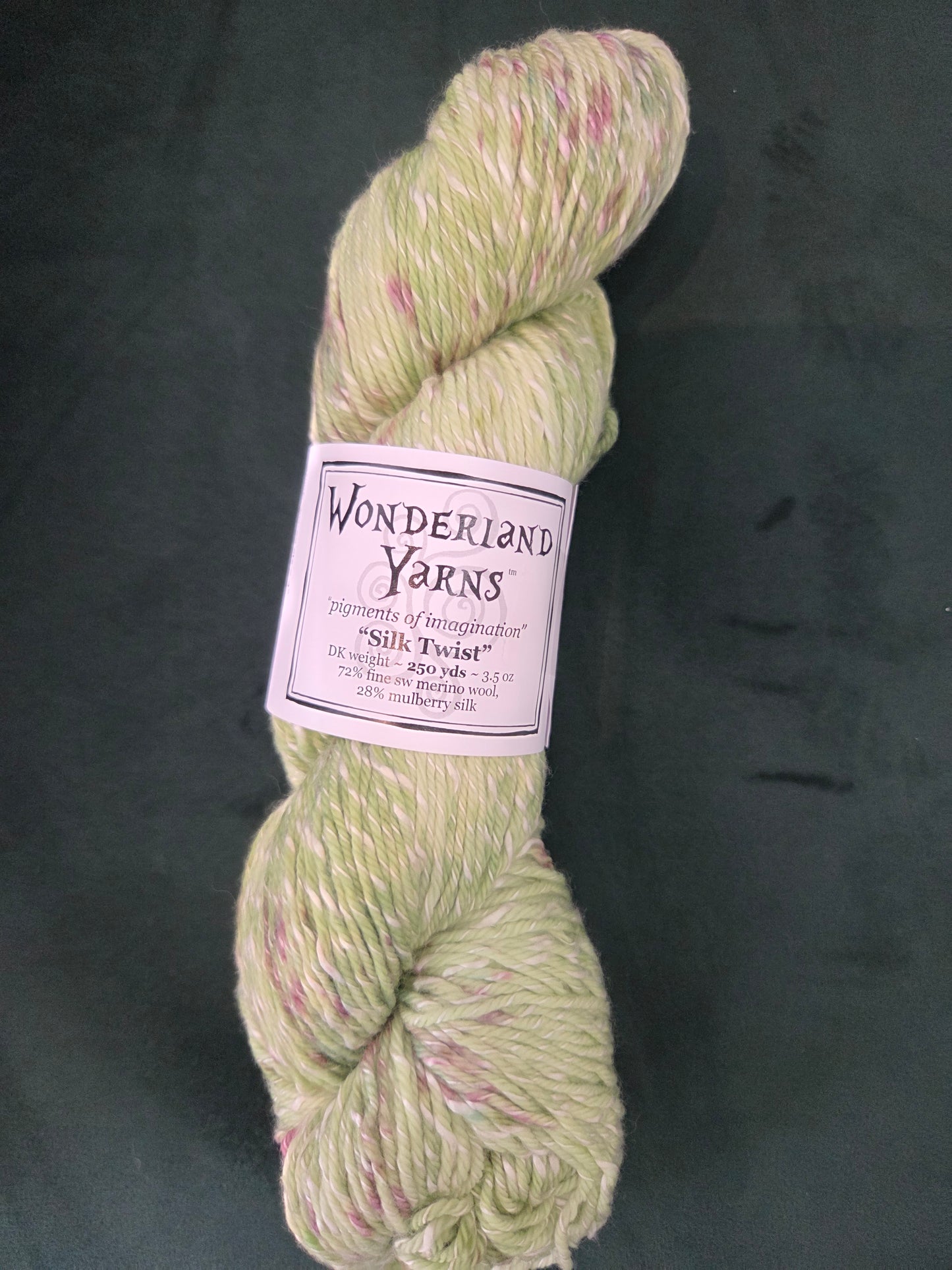 Frabjous Fibers skein of Wonderland Yarns Silk Twist light green yarn with pink speckles and label