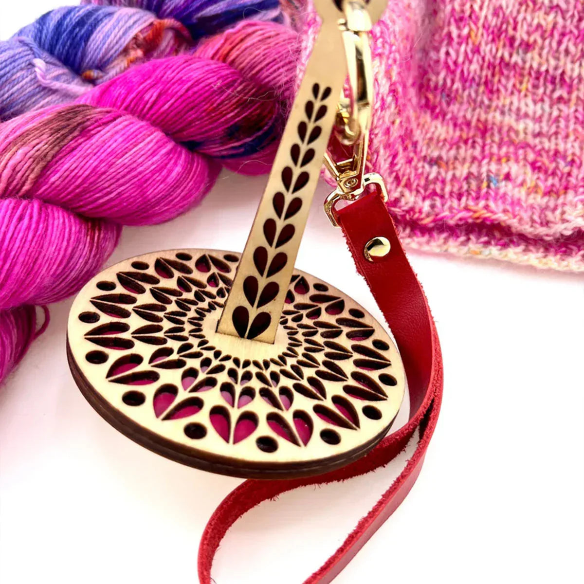 Laser-cut wooden yarn minder tool with heart design, red strap, and colorful yarn – AriYARN Shop & Studio