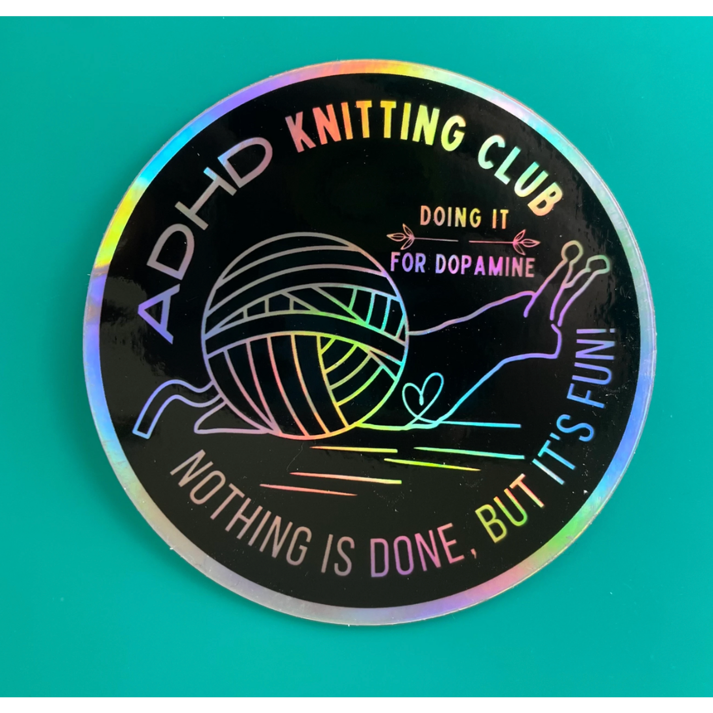 Holographic round sticker featuring yarn and needles with ADHD Knitting Club text and slogan fun knitting stickers for craft…
