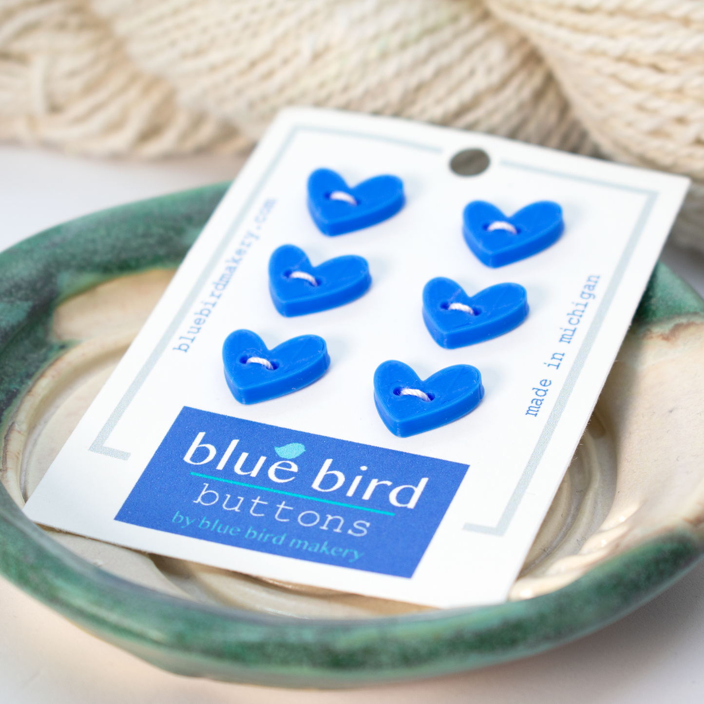 Blue heart-shaped buttons by Blue Bird Makery displayed in a bowl, 12mm size