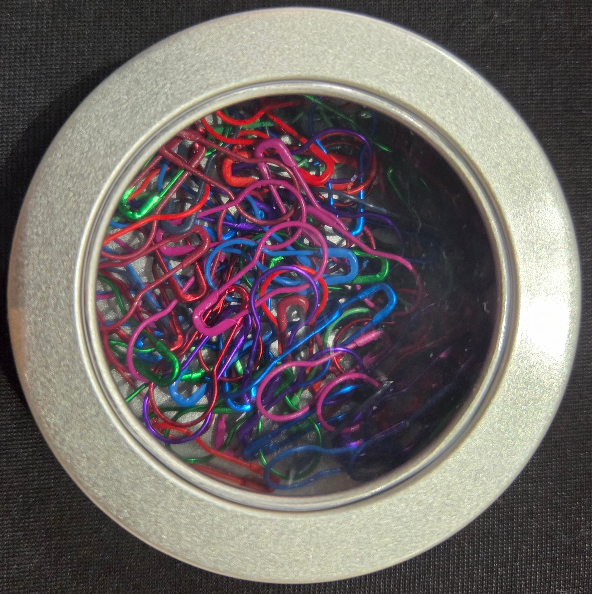 AriYARN stitch marker set in round silver tin with clear lid showing colorful loop stitch markers for knitting