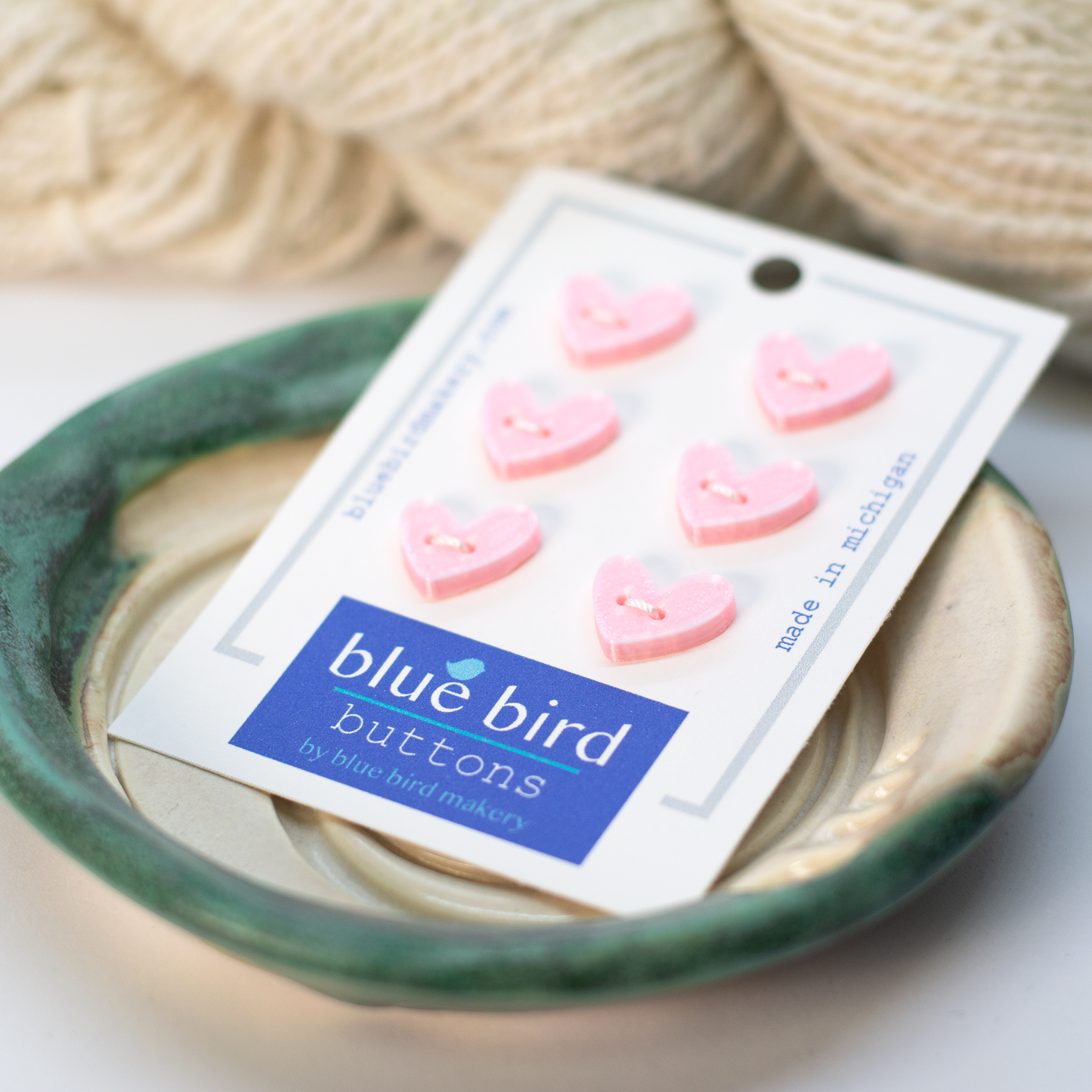 Pink 12mm craft buttons in heart shapes on a packaging card from Blue Bird Makery