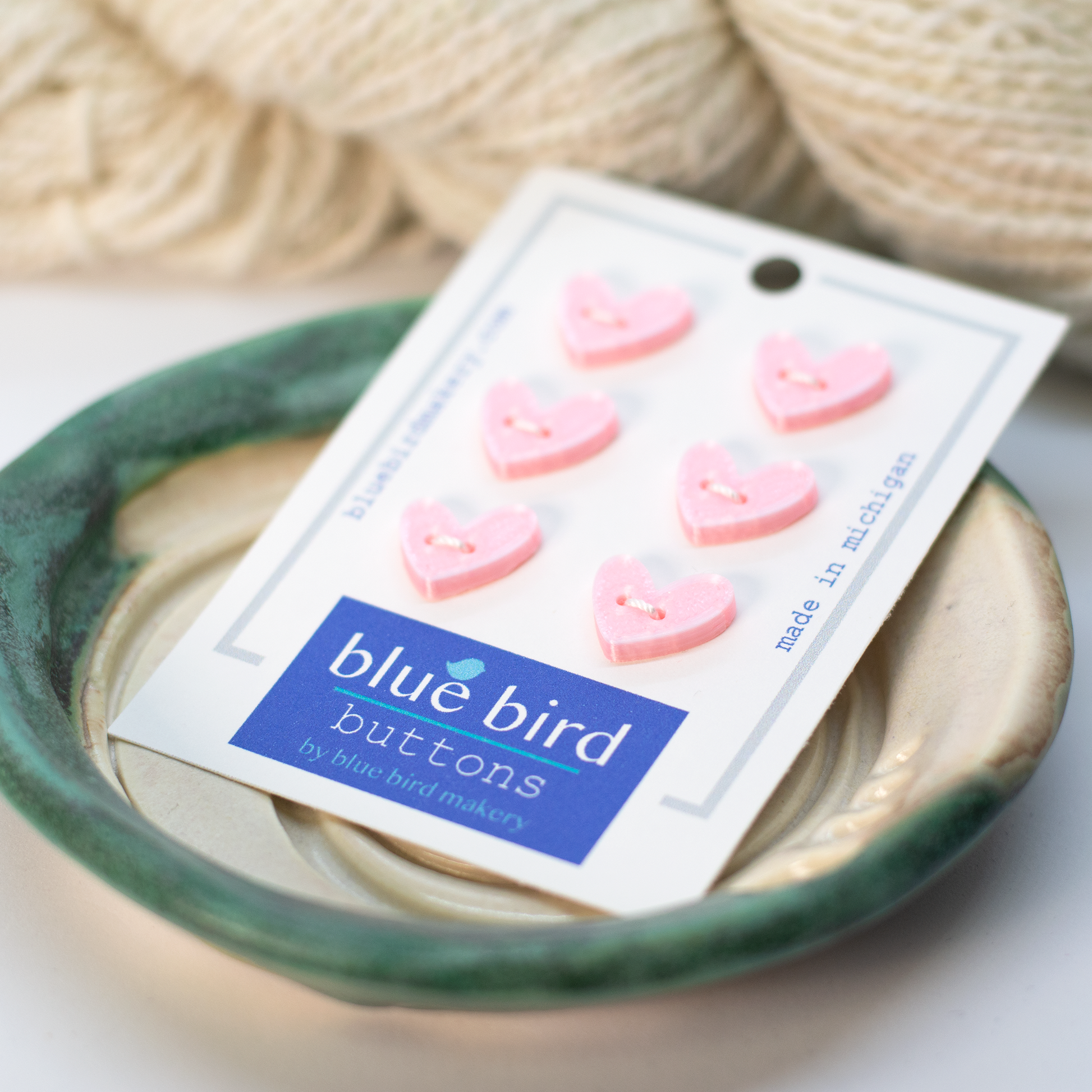 Pink 12mm craft buttons in heart shapes on a packaging card from Blue Bird Makery