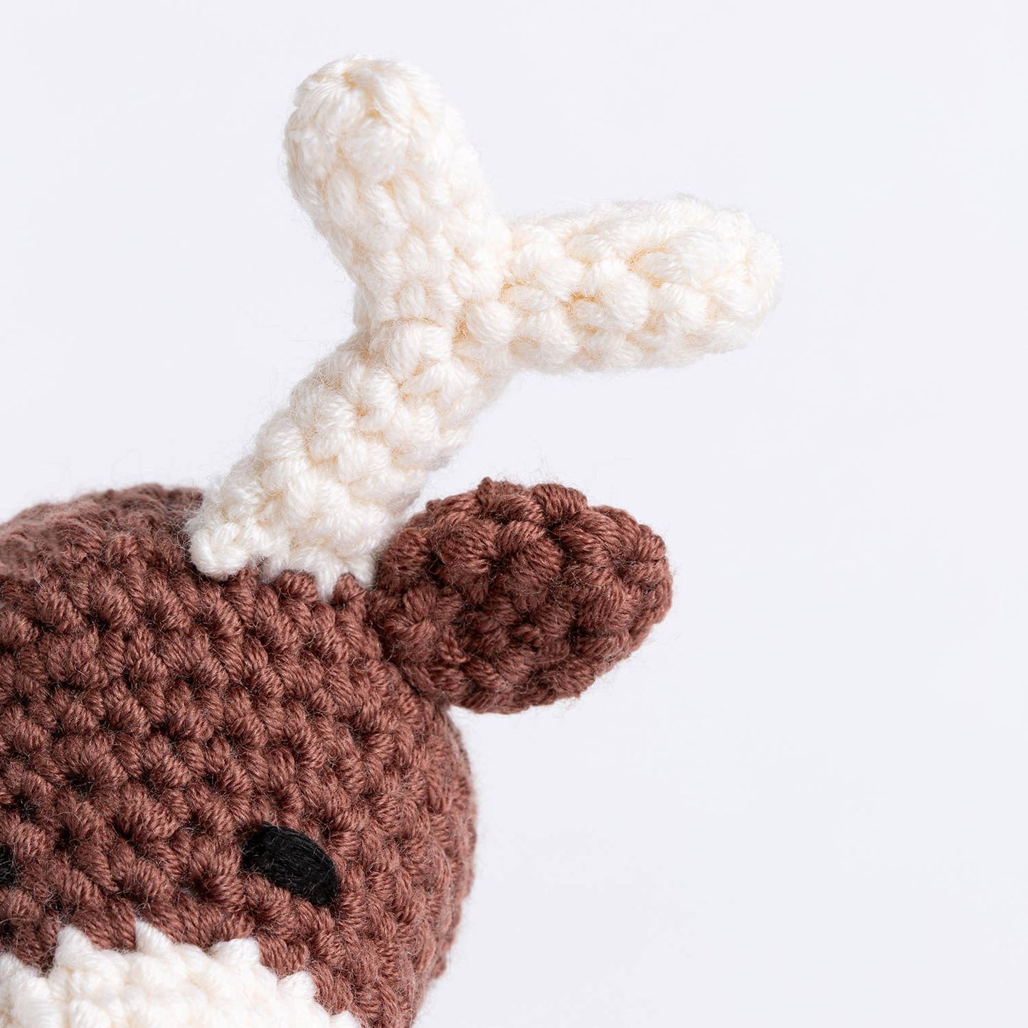 Belle the Reindeer crochet pattern close up of brown crocheted reindeer head with white antler and ear