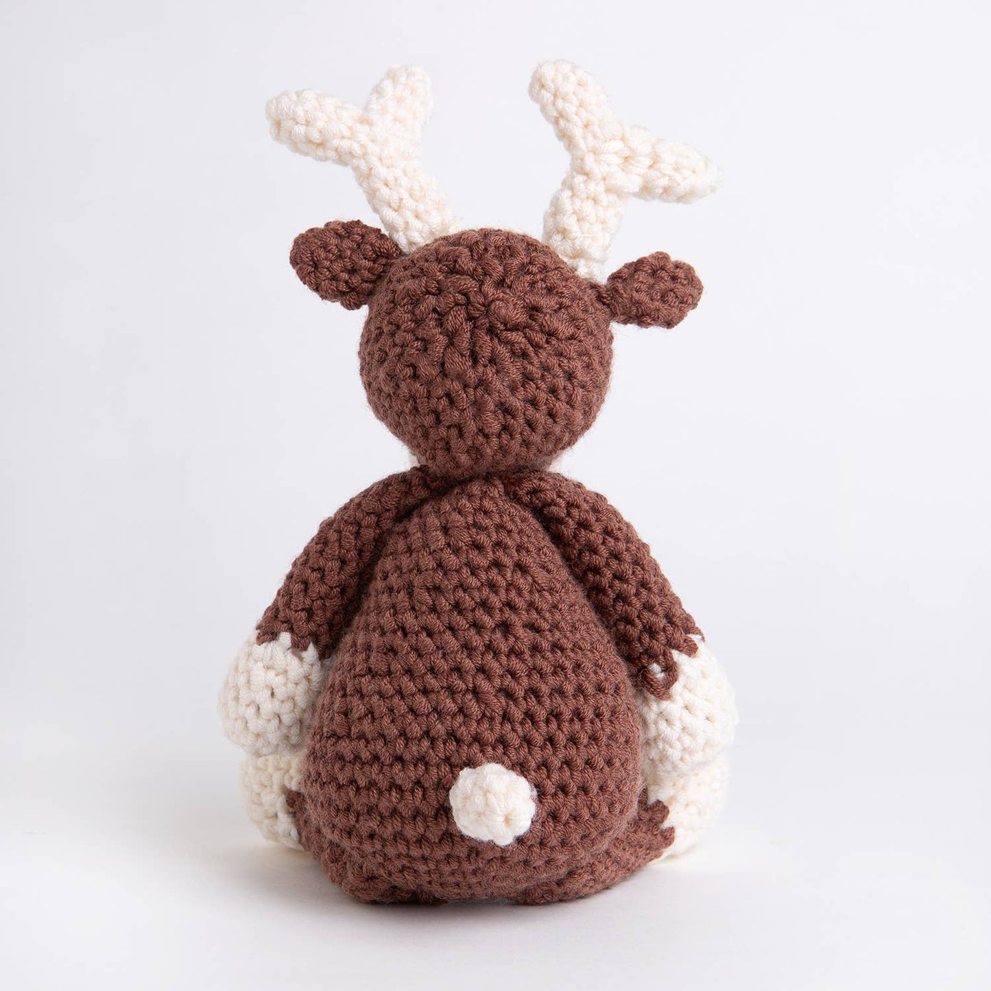 Belle the Reindeer crochet pattern brown amigurumi reindeer with cream antlers and paws shown from back on white background