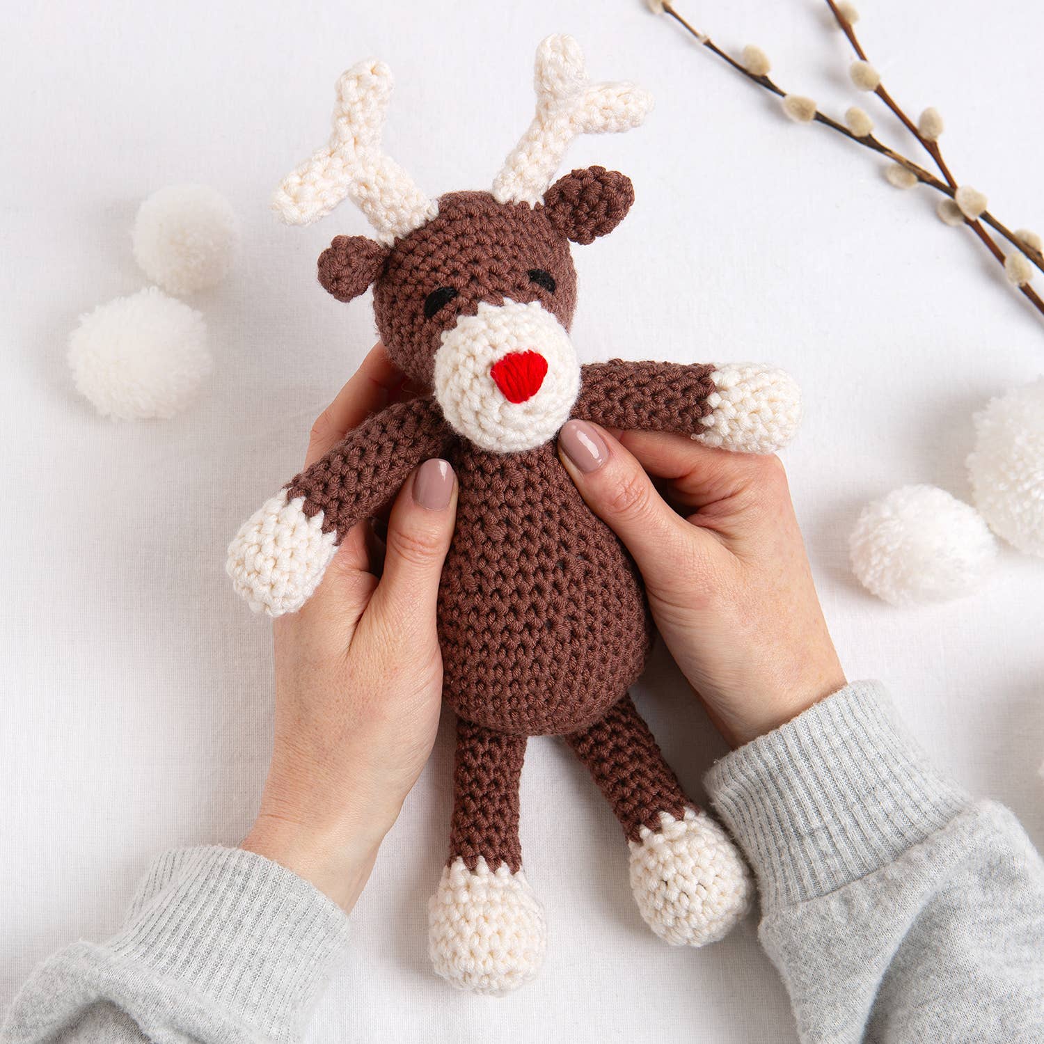 Belle the Reindeer crochet pattern brown and white amigurumi reindeer with red heart nose held in hands