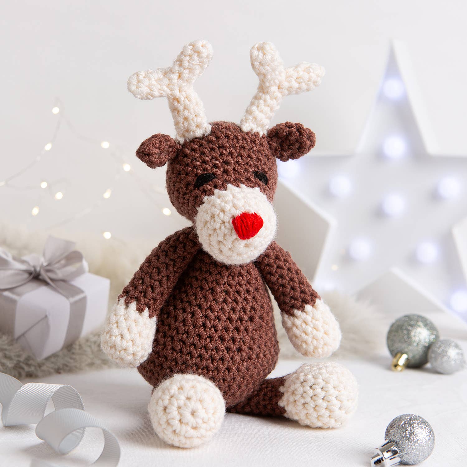 Belle the Reindeer crochet pattern brown reindeer with cream antlers and paws red nose sitting with holiday lights and ornam…