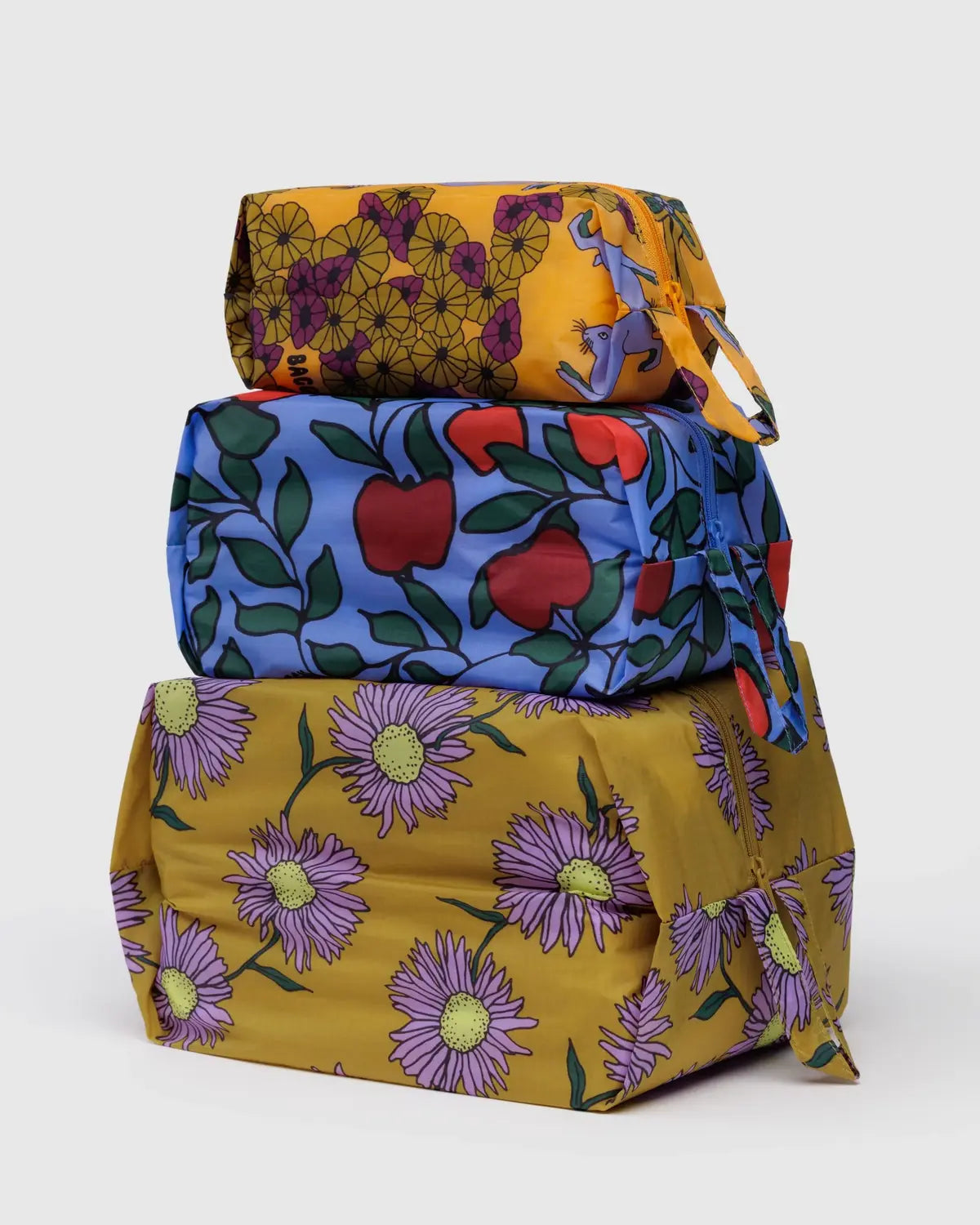 Baggu 3D Zip Set in colorful floral and fruit patterns stacked together for convenient storage