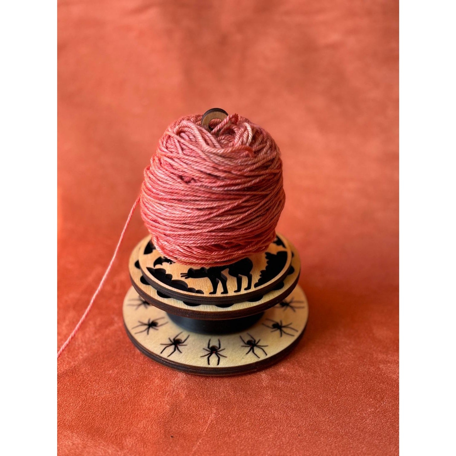 Lemonwood black widow yarn holder with pink yarn and intricate animal design