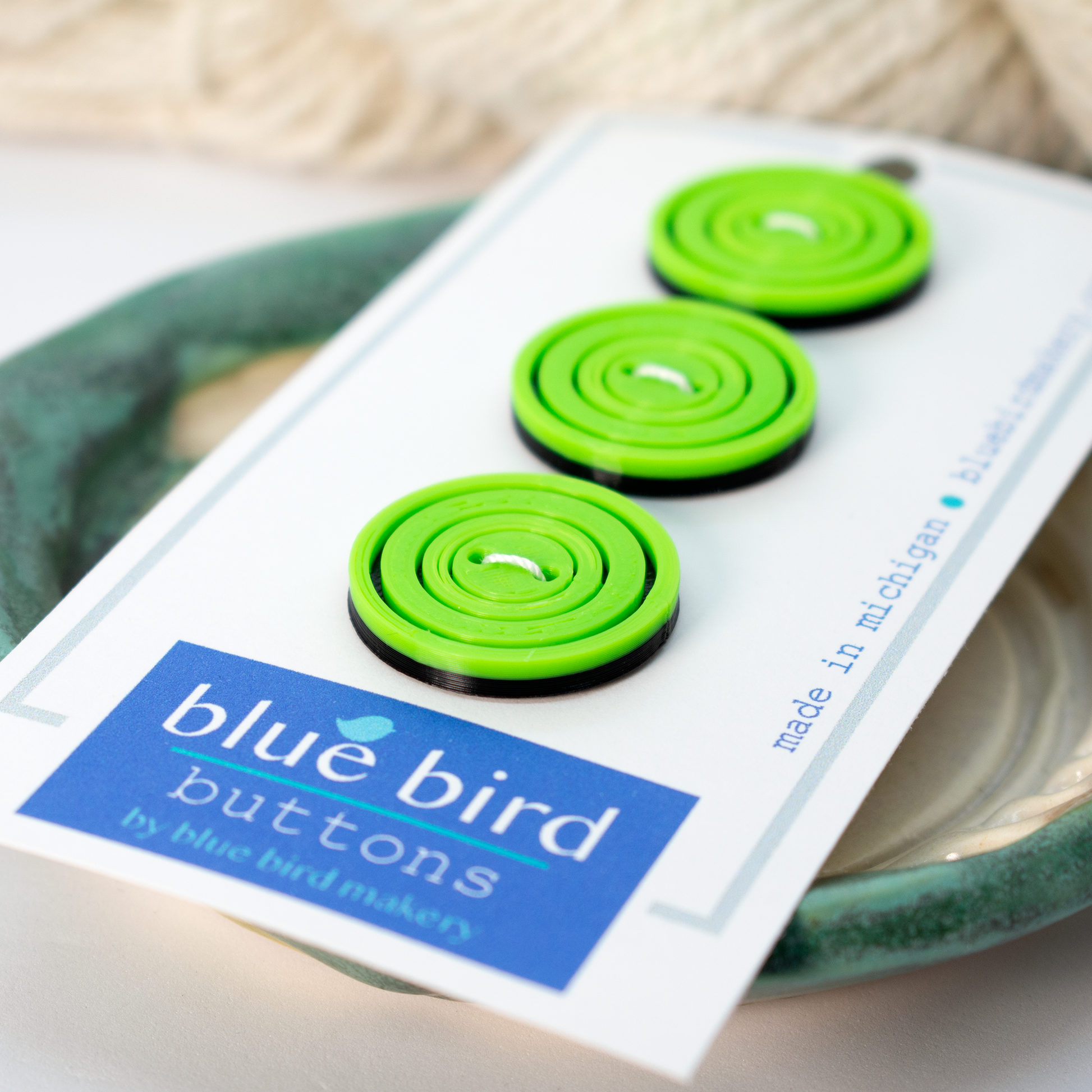 Set of three vibrant green blue bird makery buttons on a card for craft projects