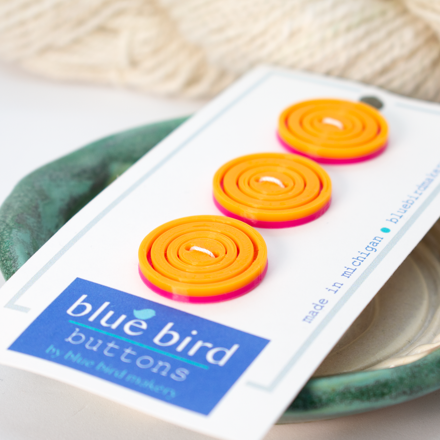 Colorful blue bird makery buttons in orange and pink on a display card for crafts and sewing projects