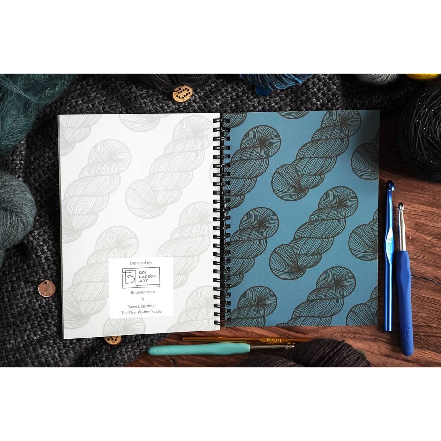 Bri Larson Art spiral bound crochet pattern organizer notebook open showing yarn skein cover and crochet hooks