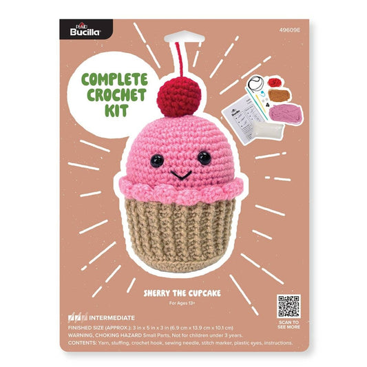 Plaid Crafts complete crochet kit packaging showing amigurumi crochet kit cupcake with pink frosting cherry and tools