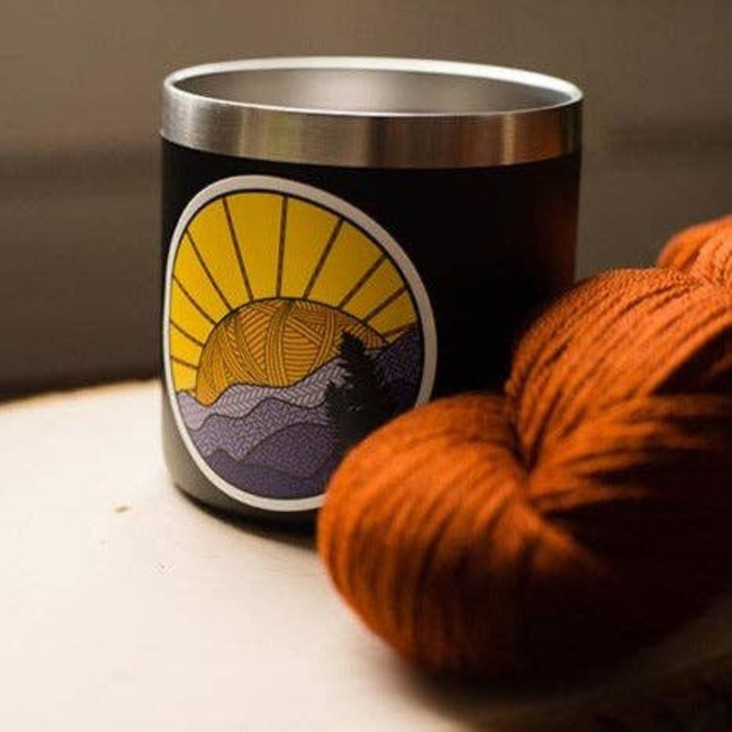 Camp Stitchwood Candle with Sunset Design and Cozy Yarn, featuring a camp sticker