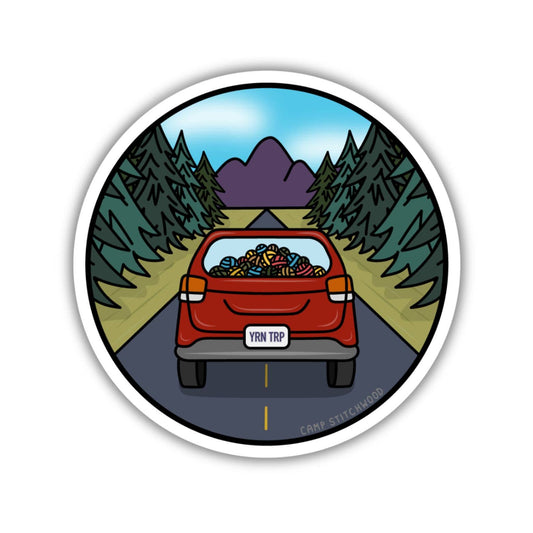 Camp sticker featuring a car filled with colorful yarn on a scenic road with mountains and trees