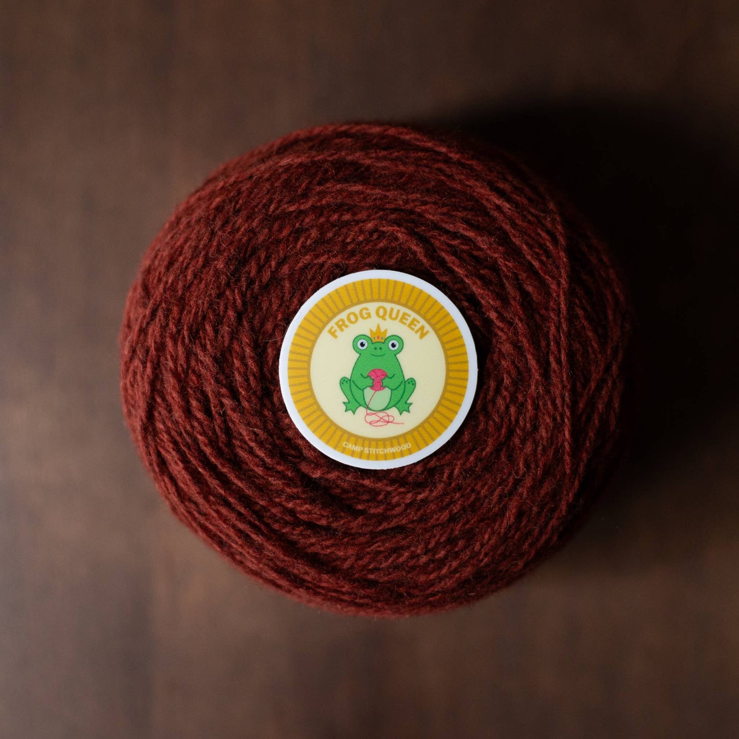 Brown yarn ball labeled Frog Queen with a colorful name badge sticker on top