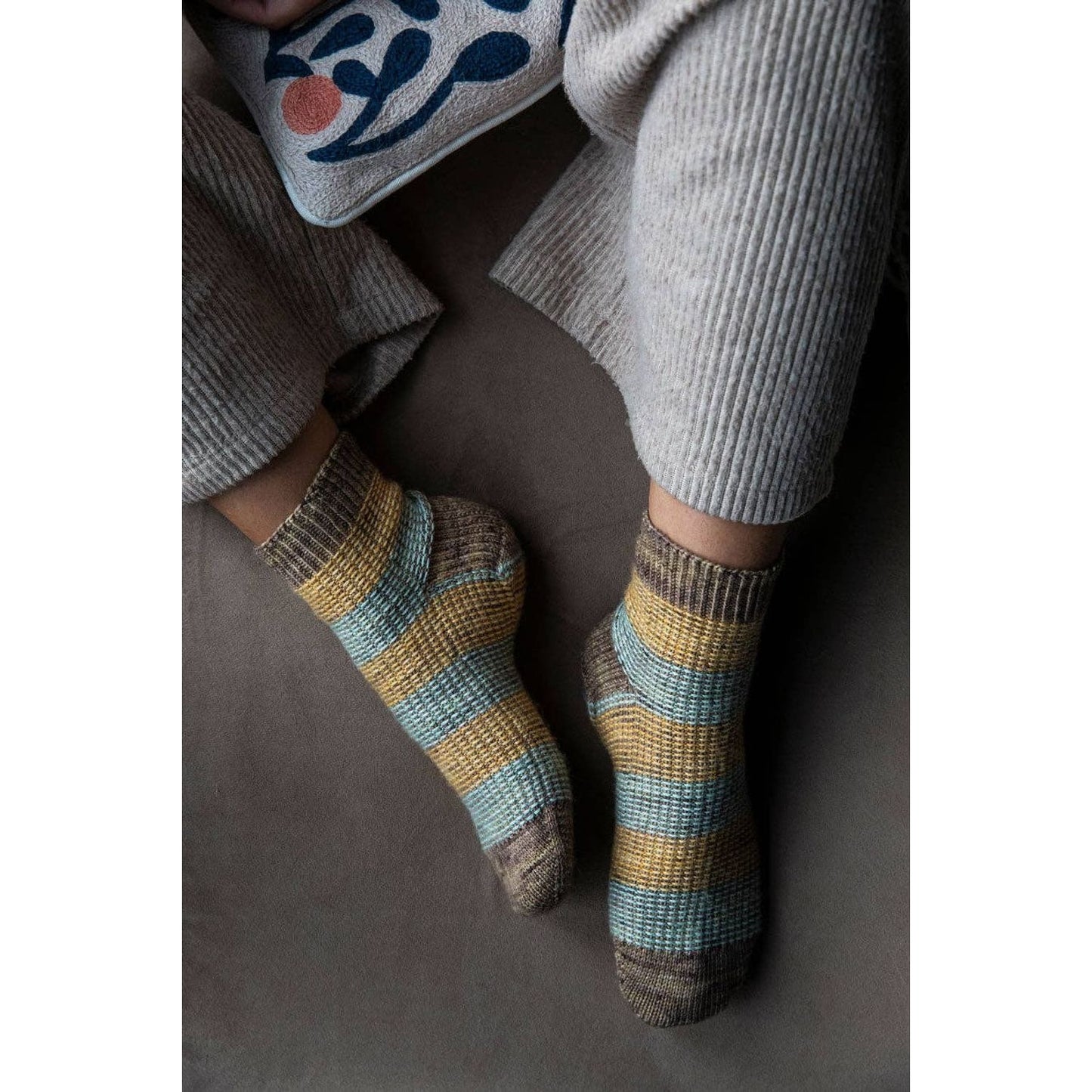 Cozy hand-knit socks with stripes in brown, yellow, and blue for chunky yarn crochet projects
