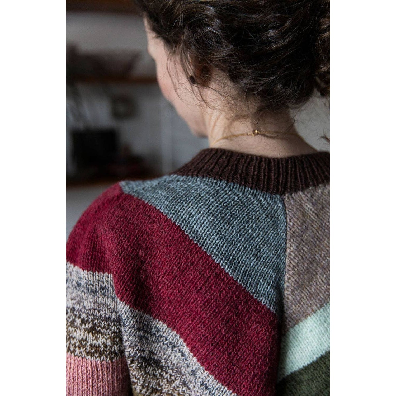 Close-up of a woman's back wearing a multicolored sweater suitable for chunky yarn crochet projects