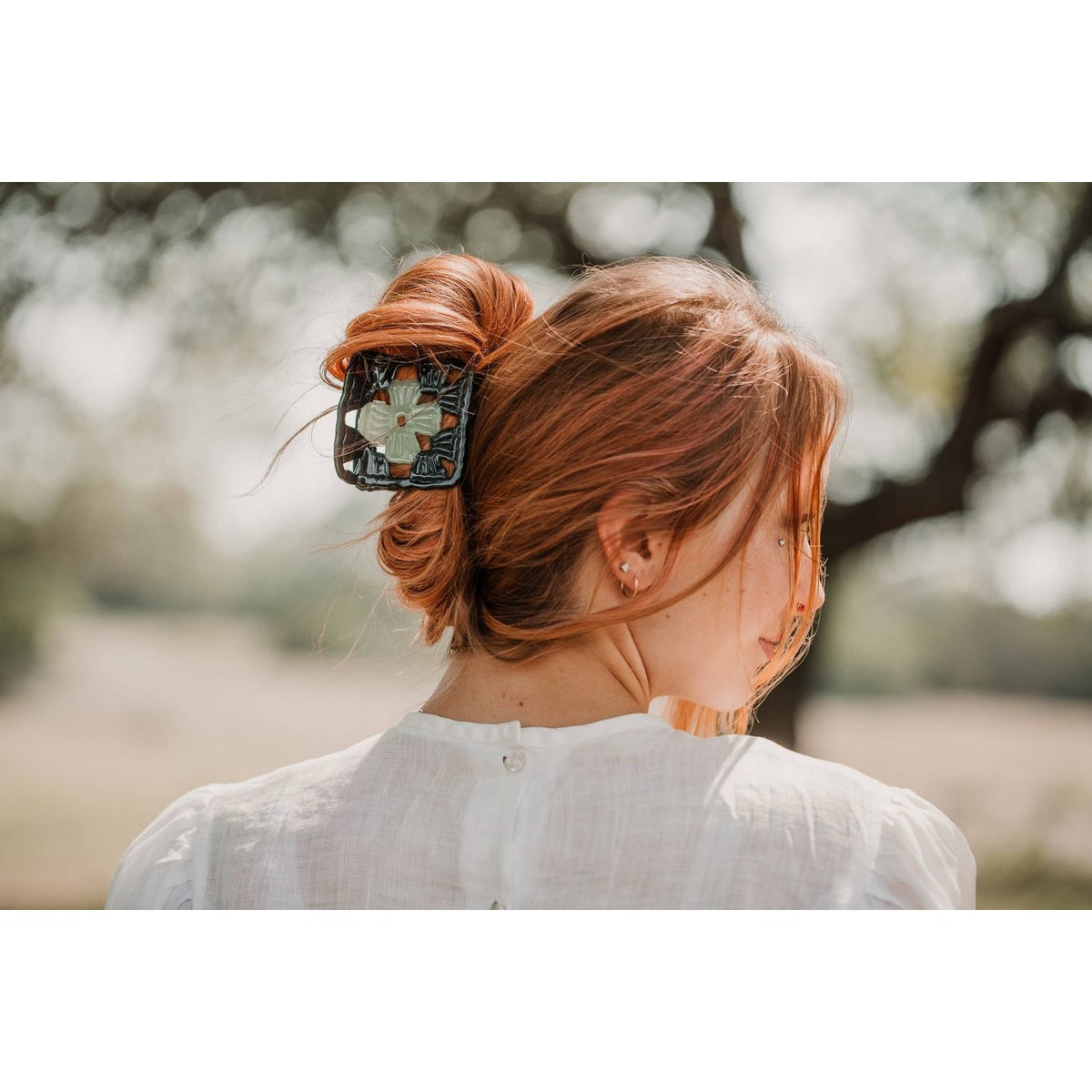 Hey Ricochet clip claw hair clip holding a stylish updo with a scenic background