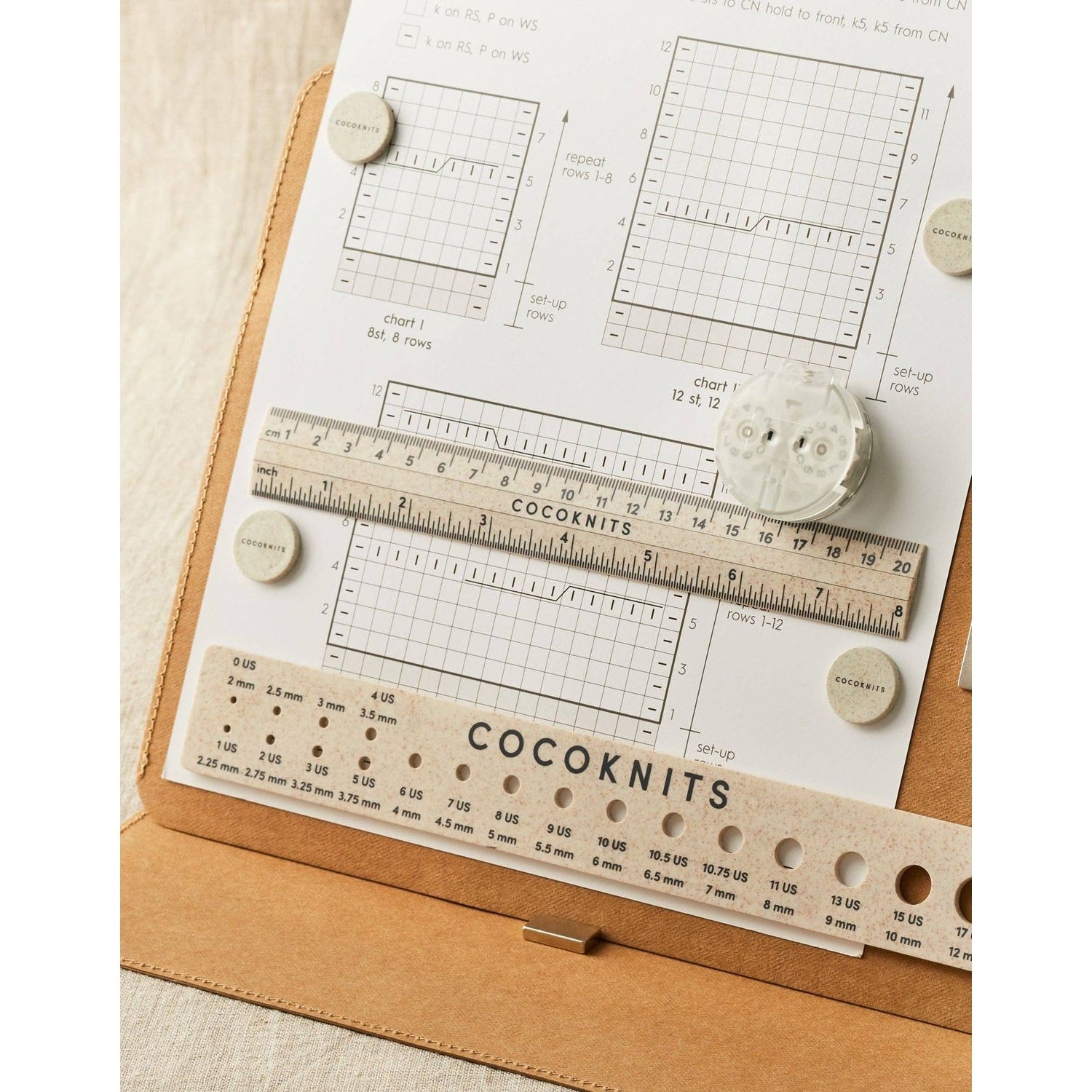 Cocoknits knitting ruler and gauge set on a craft paper planner with charts and buttons