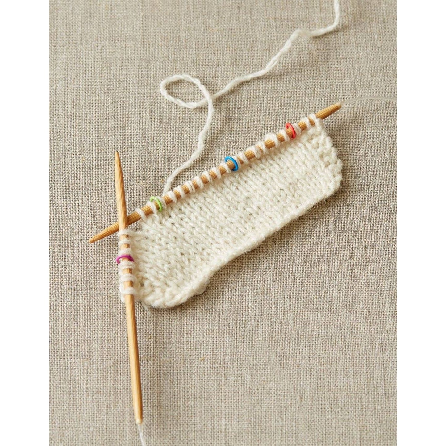 Cocoknits ring stitch markers set on knitting needles holding cream yarn for easy pattern tracking