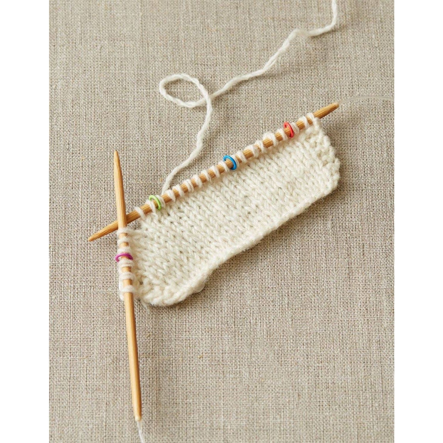 Cocoknits ring stitch markers set on knitting needles holding cream yarn for easy pattern tracking