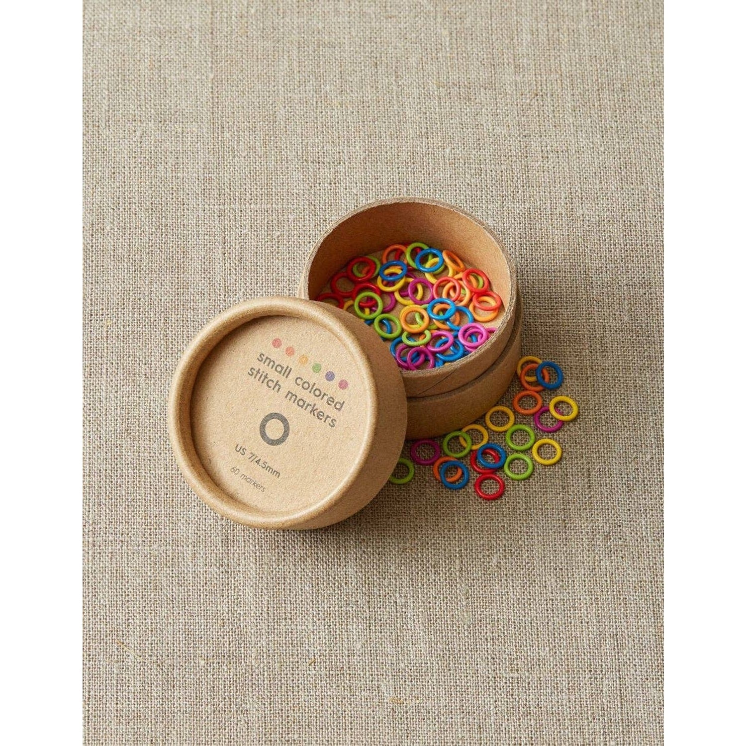 Cocoknits ring stitch markers in a round container with colorful markers for knitting projects