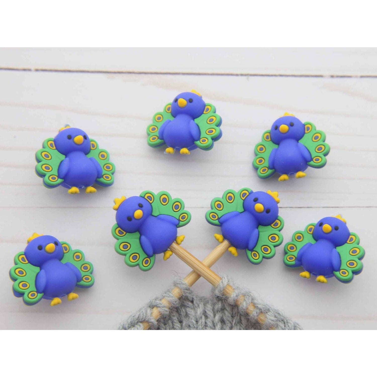 Set of colorful peacock stitch markers for knitting, featuring vibrant blue peacocks with green feathers