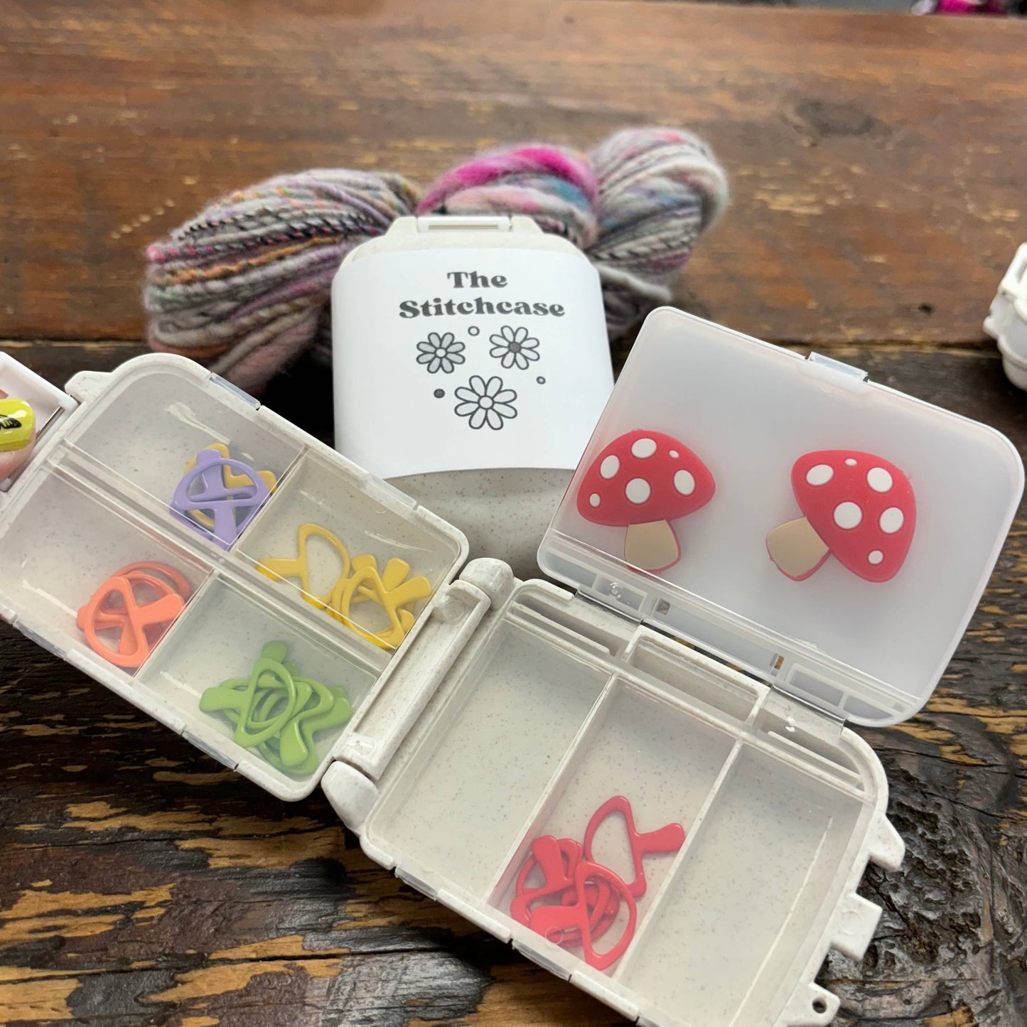compact knitting crochet case with divided compartments holding colorful stitch markers and mushroom closures