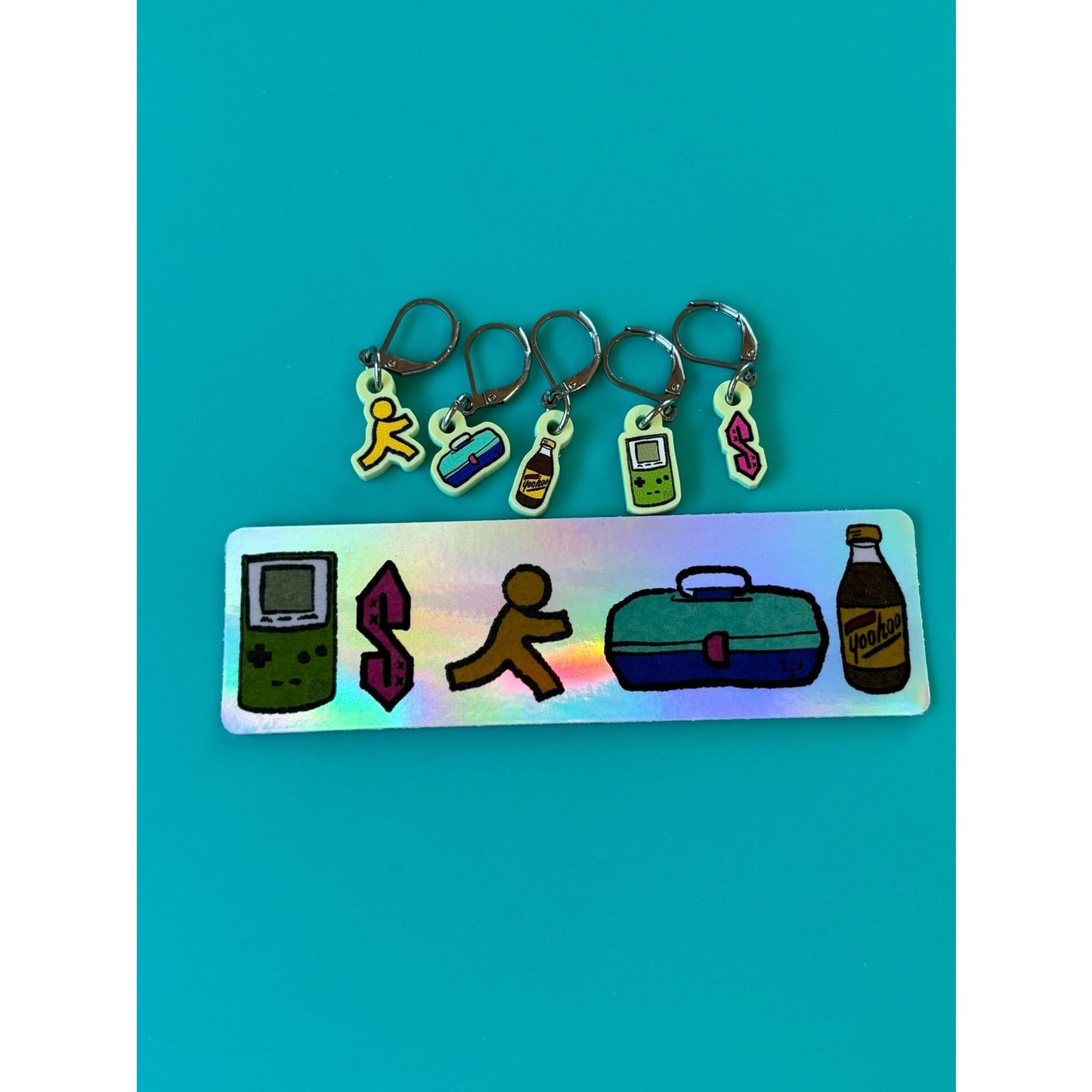 nostalgic 90s kid knitting accessories holographic tag with five stitch marker charms Game Boy running dollar sign lunchbox