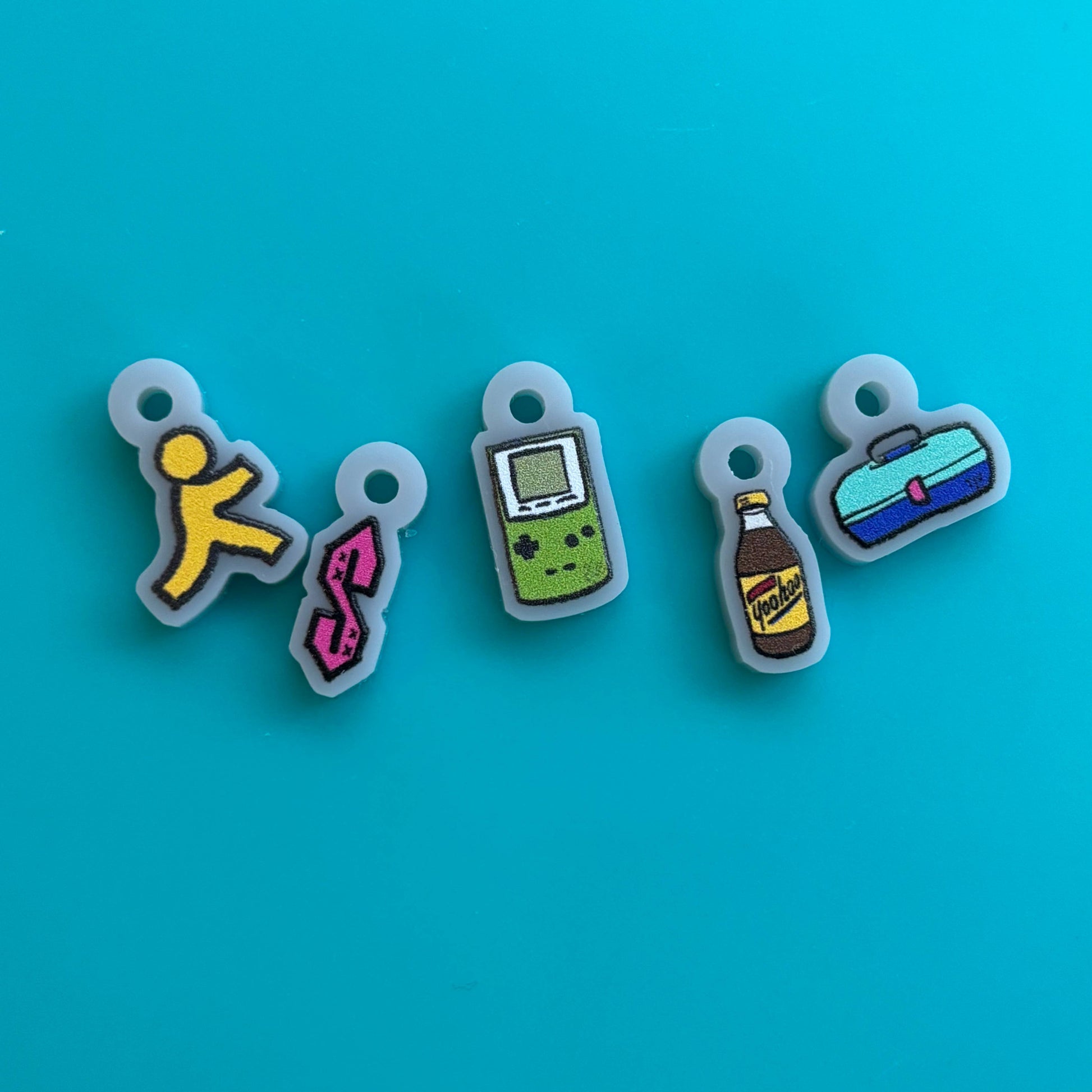 nostalgic 90s kid knitting accessories five colorful stitch markers showing Game Boy soda bottle fanny pack running man